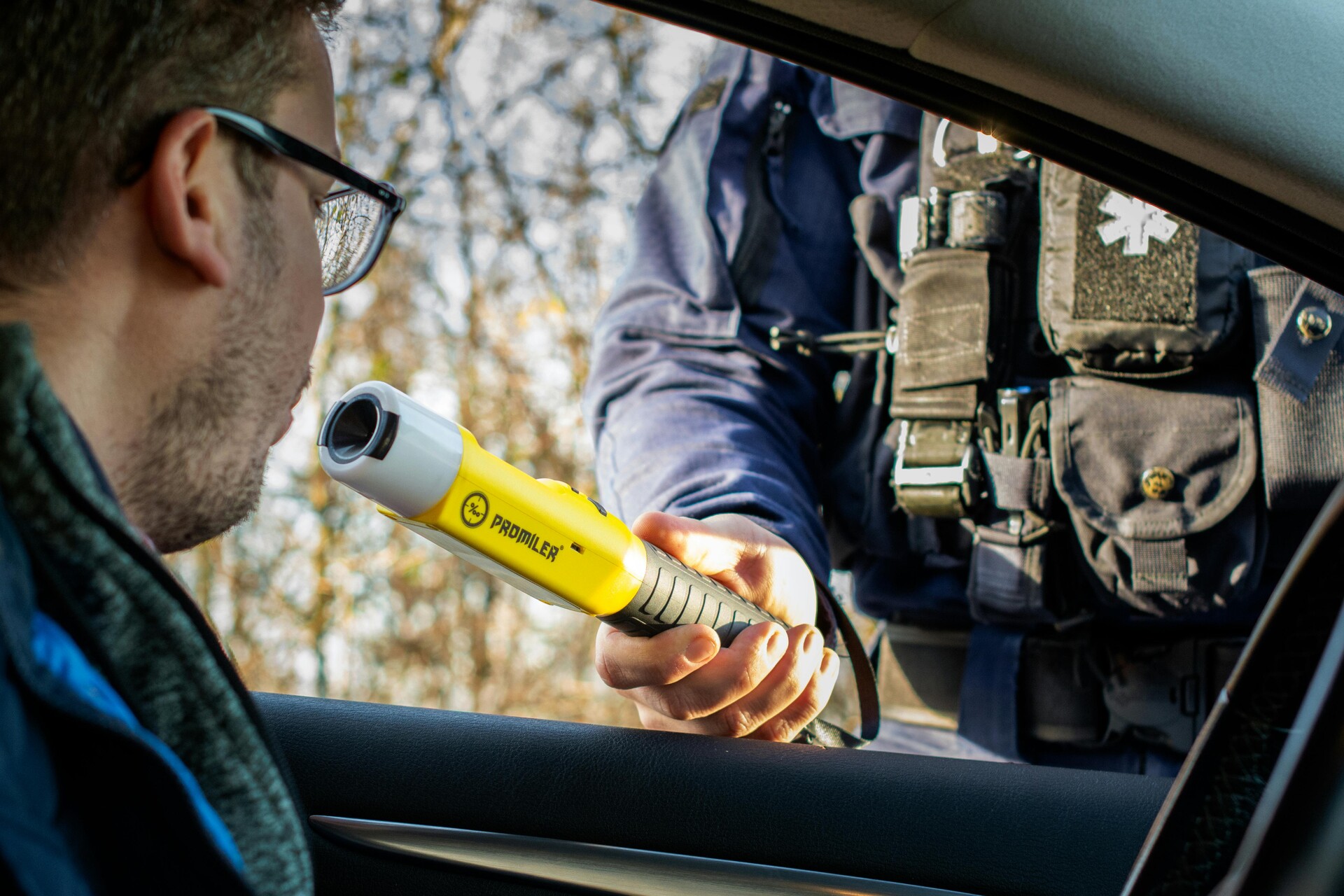 Police officer conducting a roadside breathalyzer test on a male driver