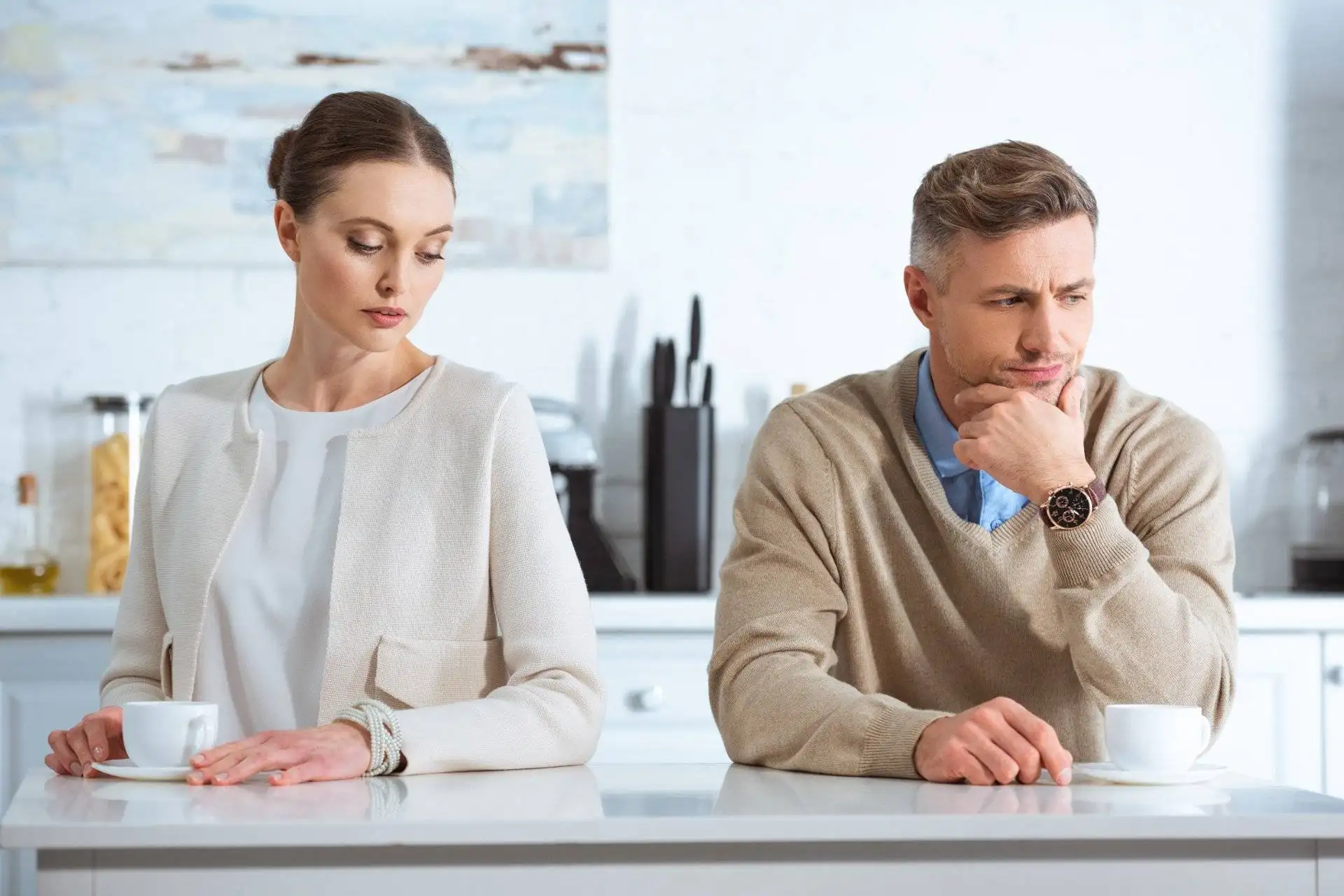 Couple sitting at kitchen table with tense expressions