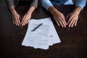 Divorcing couple sitting at table with rings and divorce documents