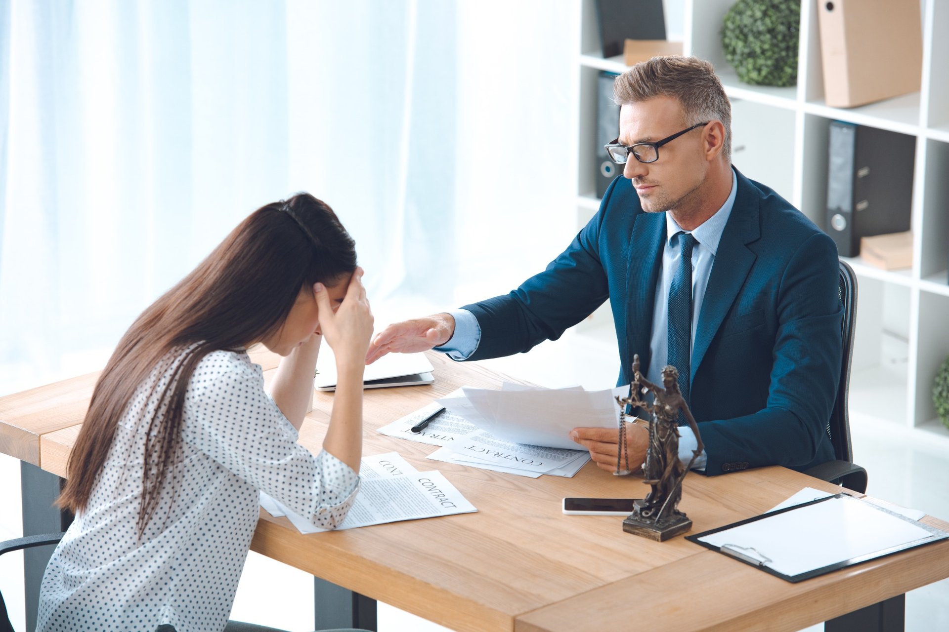 Lawyer consoling distressed female client during legal consultation