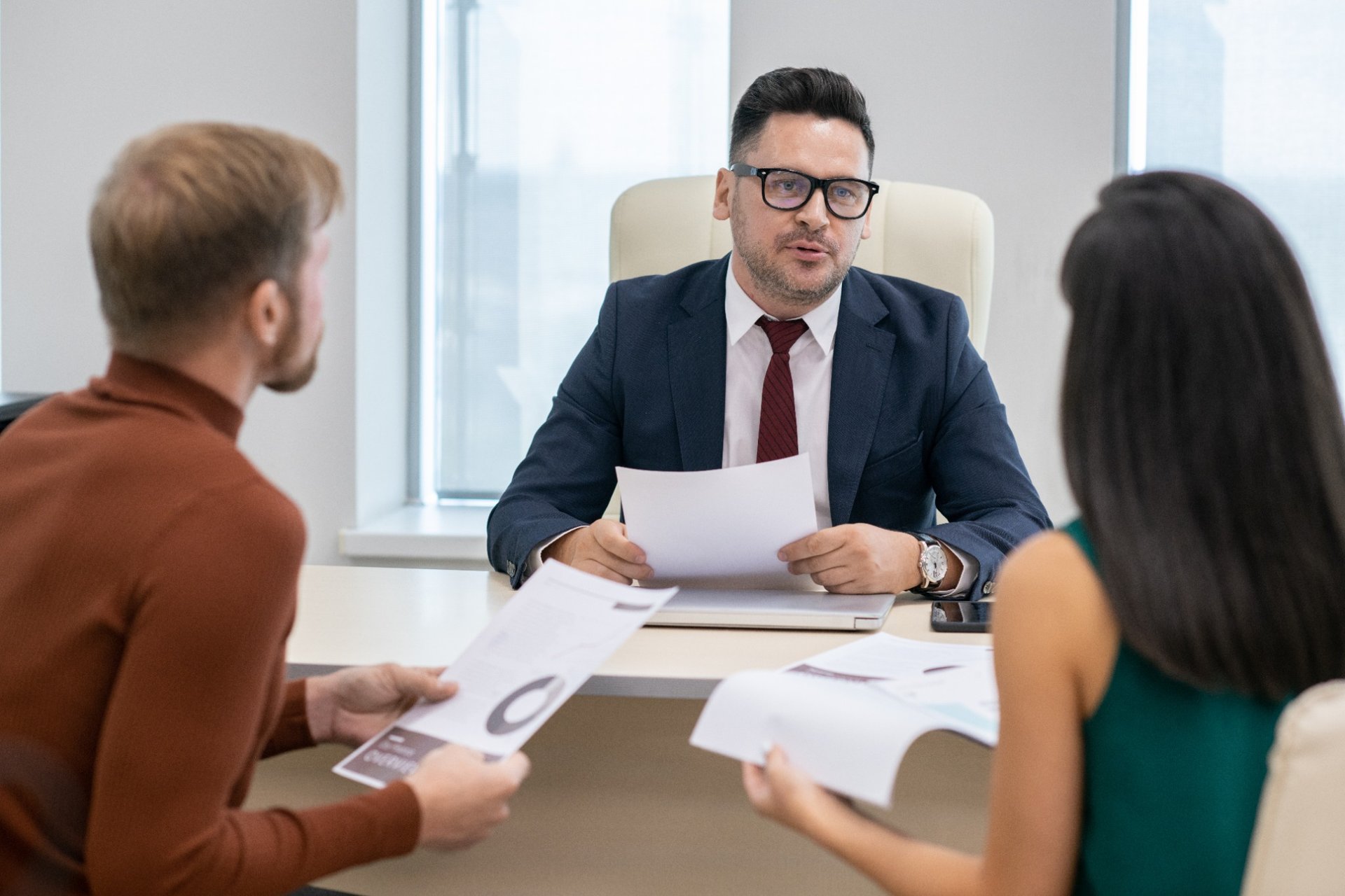 Mature businessman speaking seriously to clients at a table