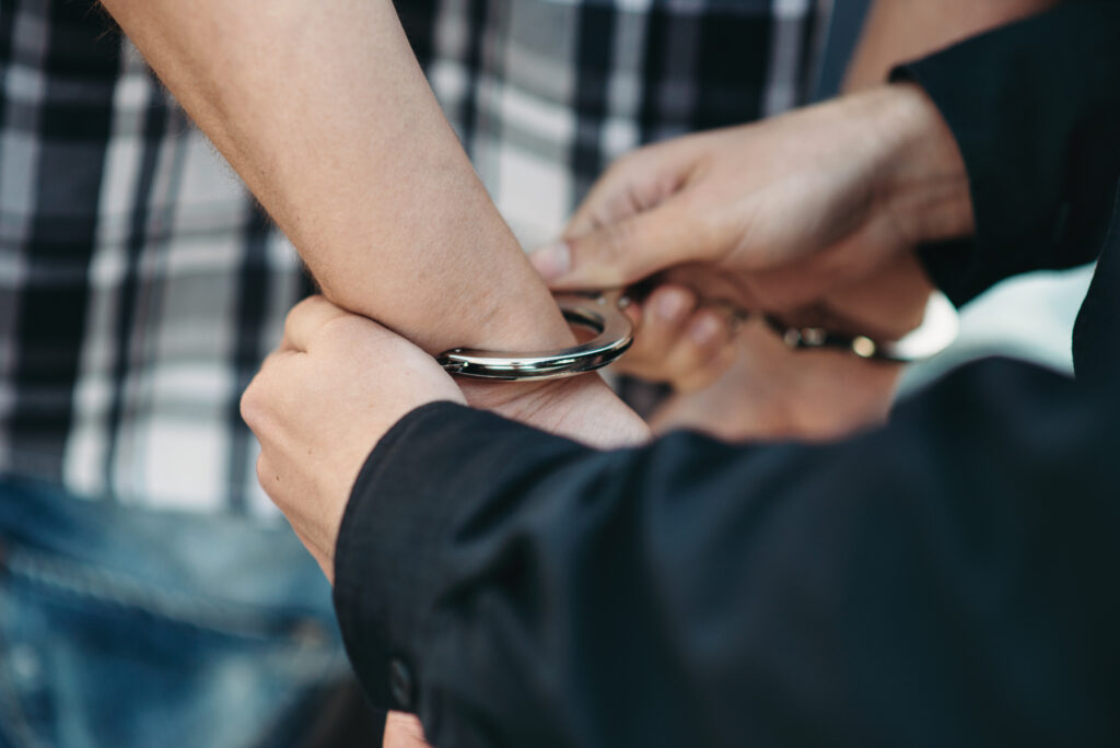 Close-up of man's wrists being placed in handcuffs by police officer