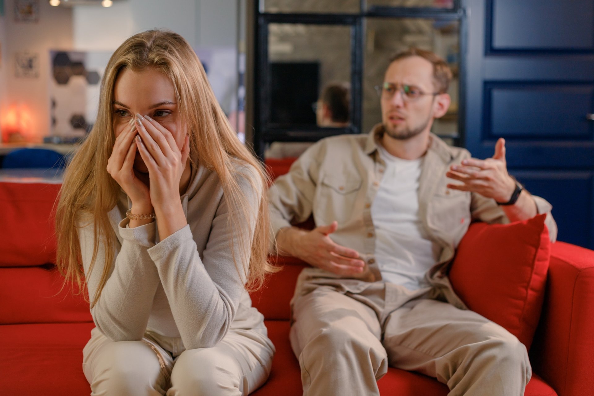 Upset woman covering her face while man gestures in frustration
