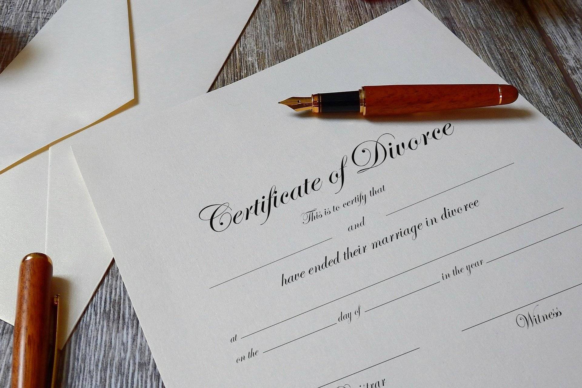 Blank divorce certificate with pen on wooden table