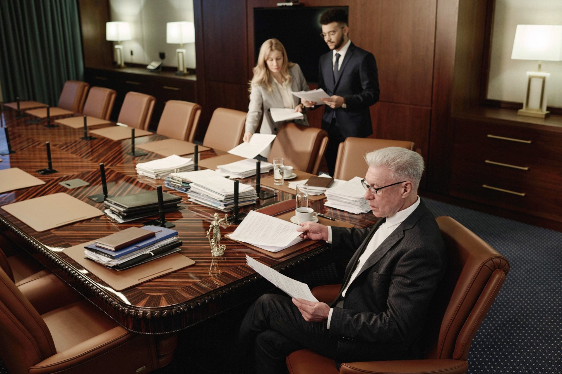 Boardroom team reviewing legal documents with piles of paperwork