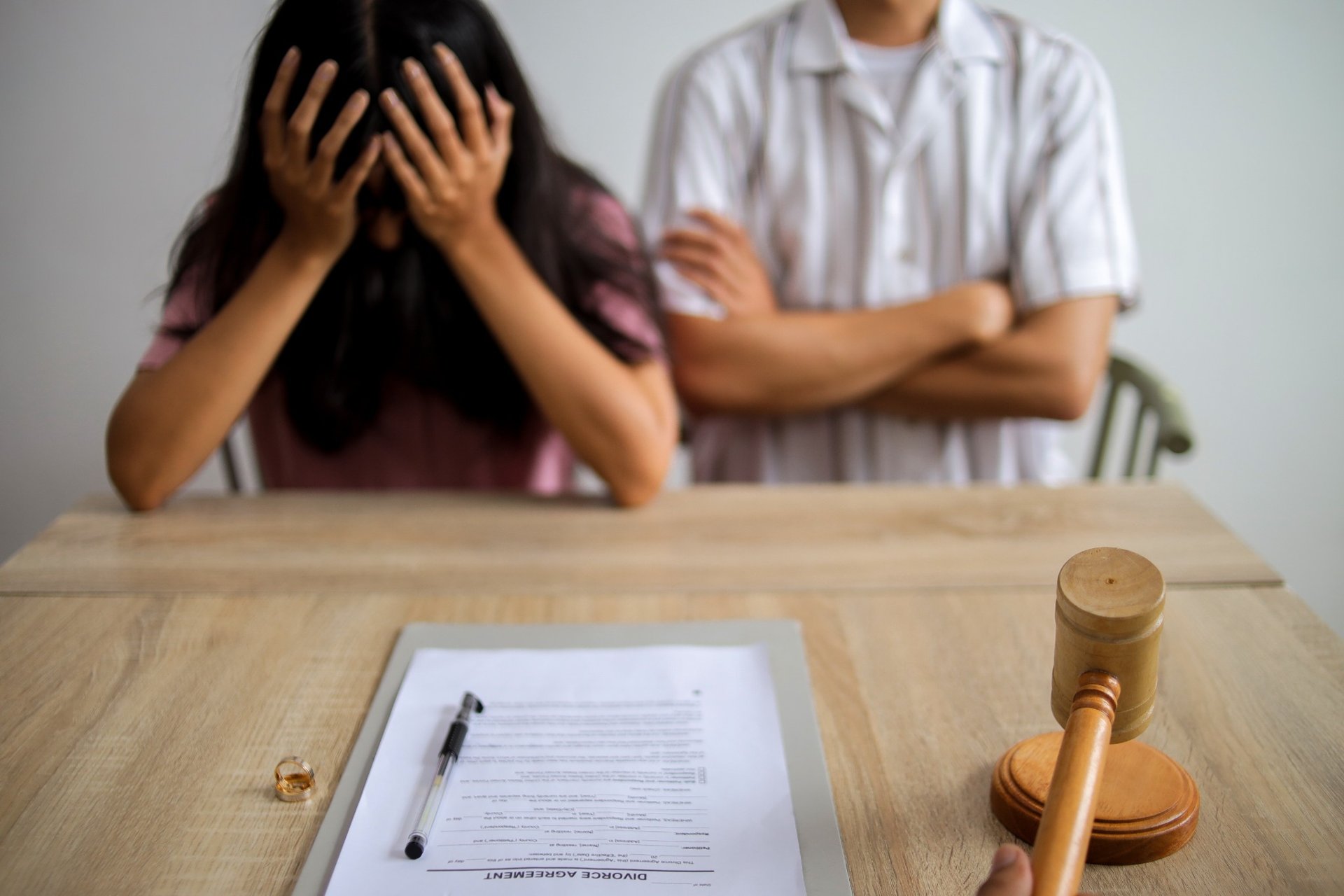 Divorcing couple sitting across from judge with agreement and rings