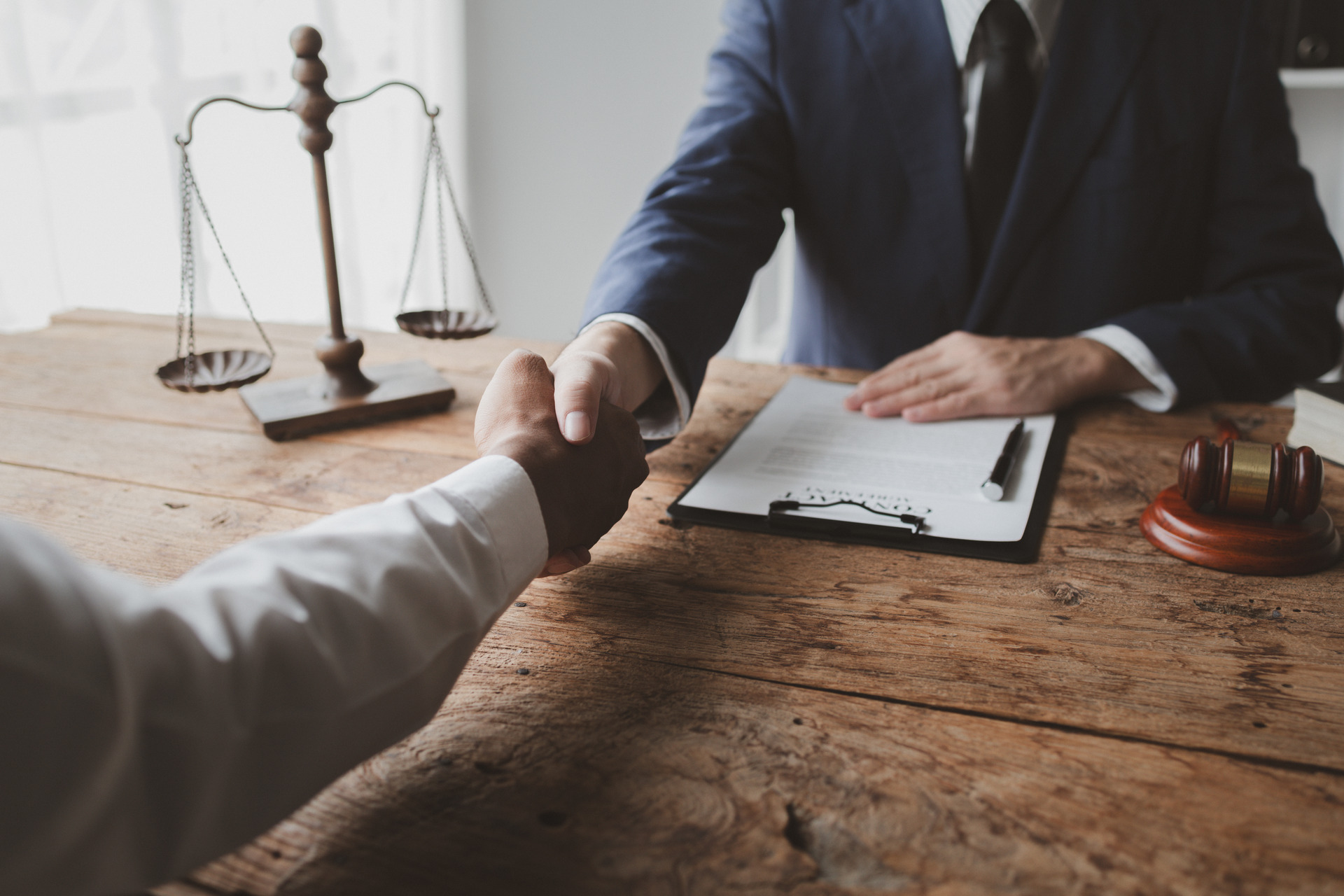 Handshake at lawyer’s office with contract