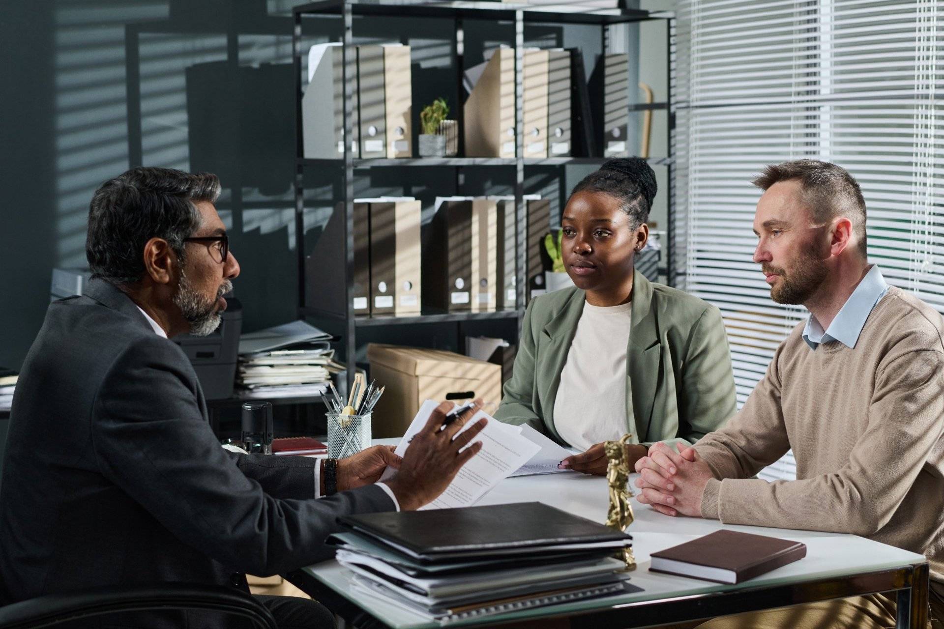 Lawyer consulting with diverse couple in modern office setting