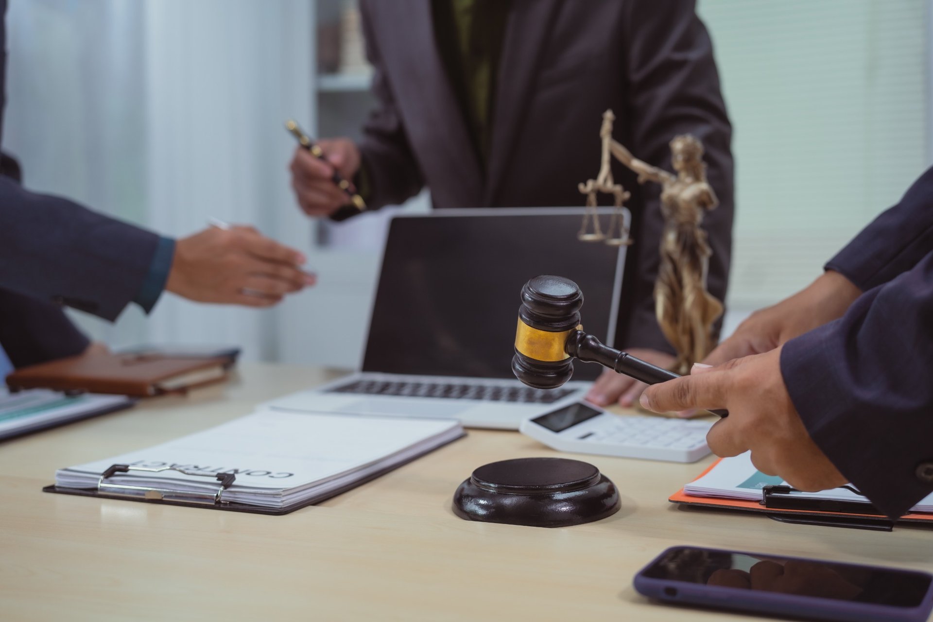 Three lawyers discussing legal strategy with documents and a gavel on the table