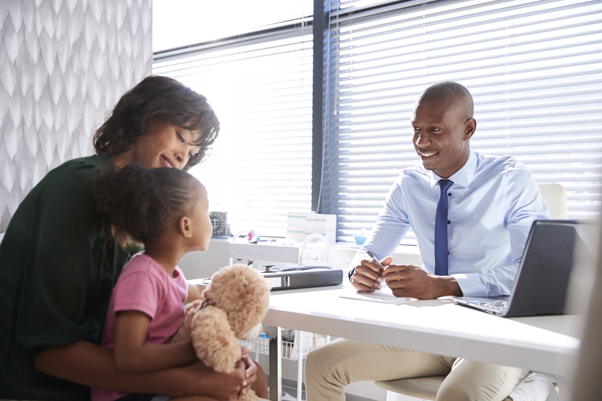 Mother and daughter in a consultation with a smiling male lawyer at a desk