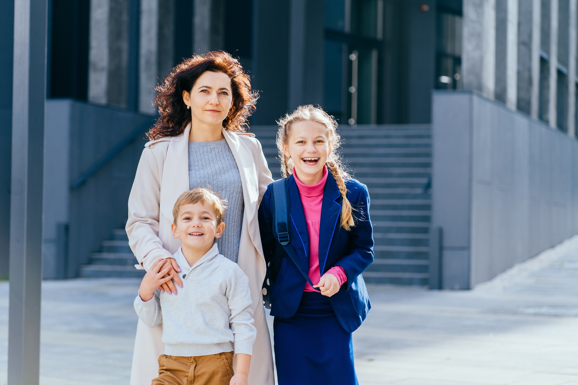 Mother standing with her two children outside a modern building