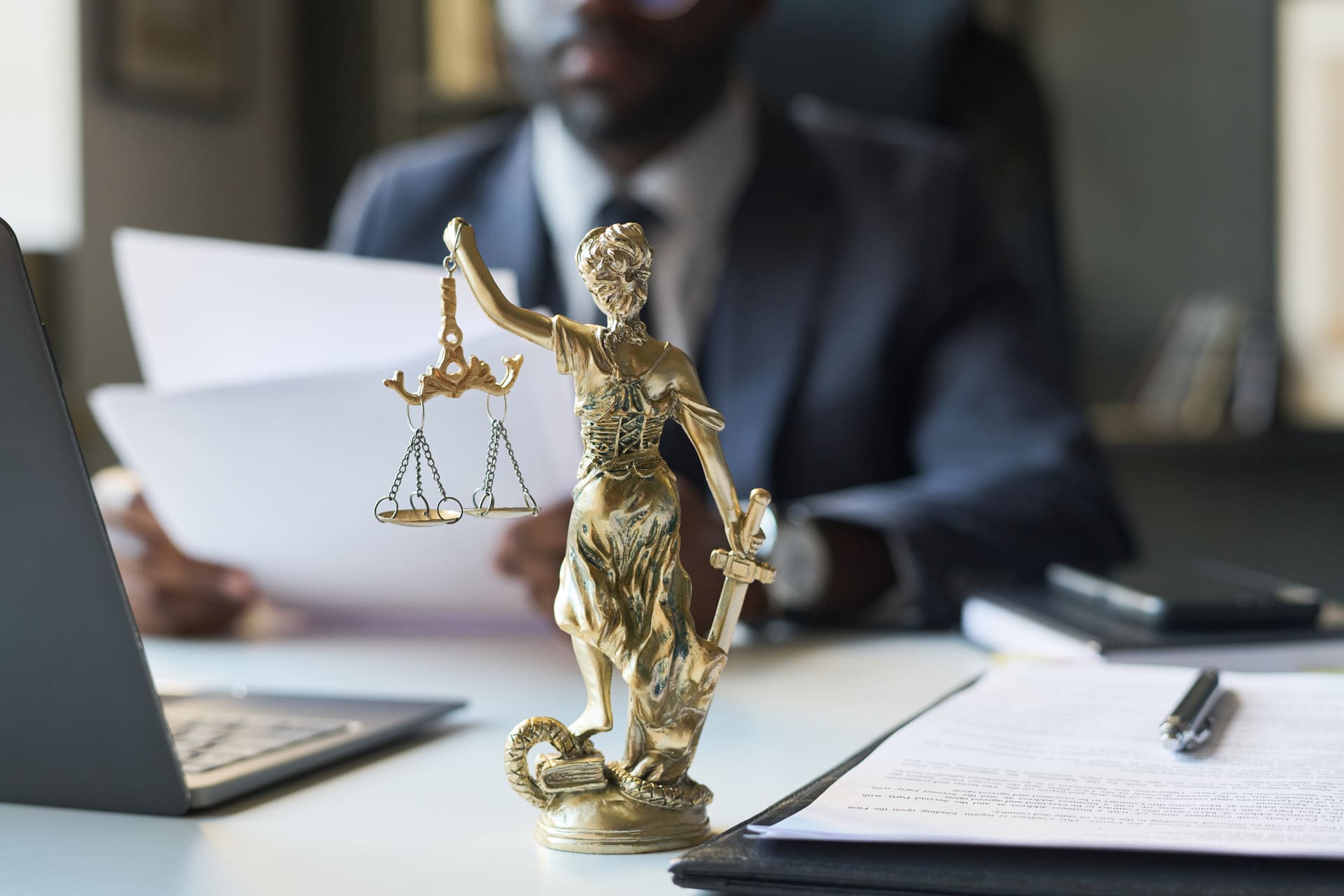 back view of lady justice statuette on lawyers desk