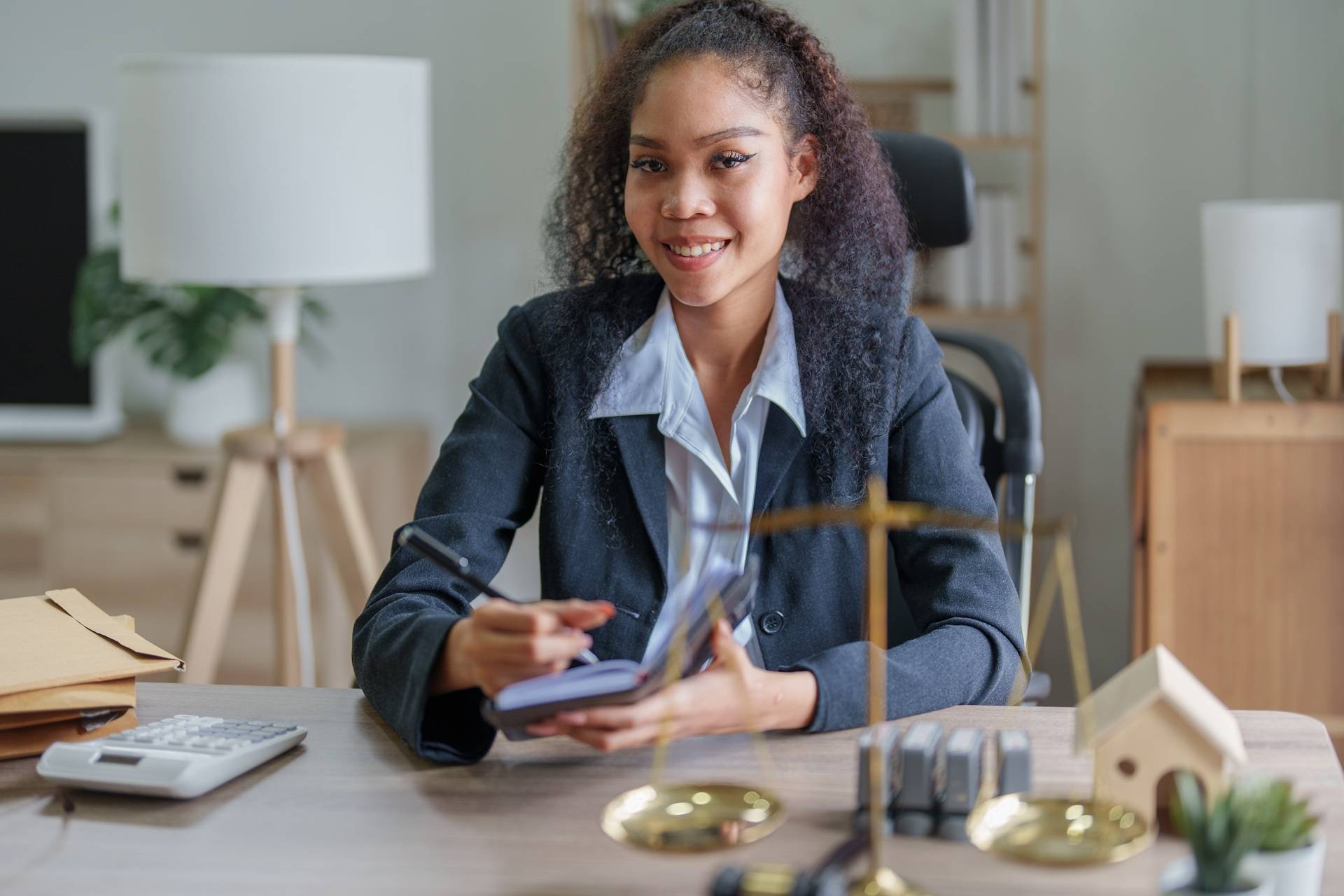 Female lawyer smiling at her desk with legal documents and scales of justice