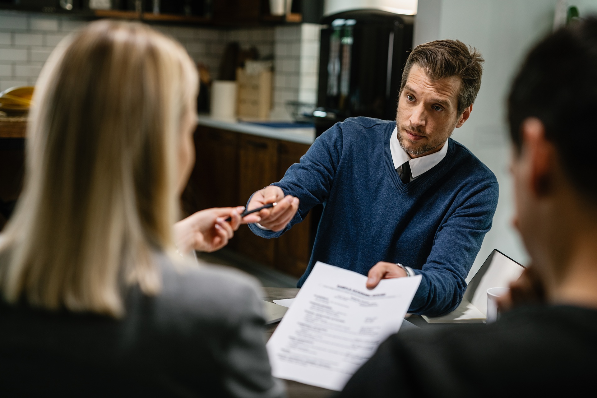Lawyer giving pen and contract to client for signing during legal meeting