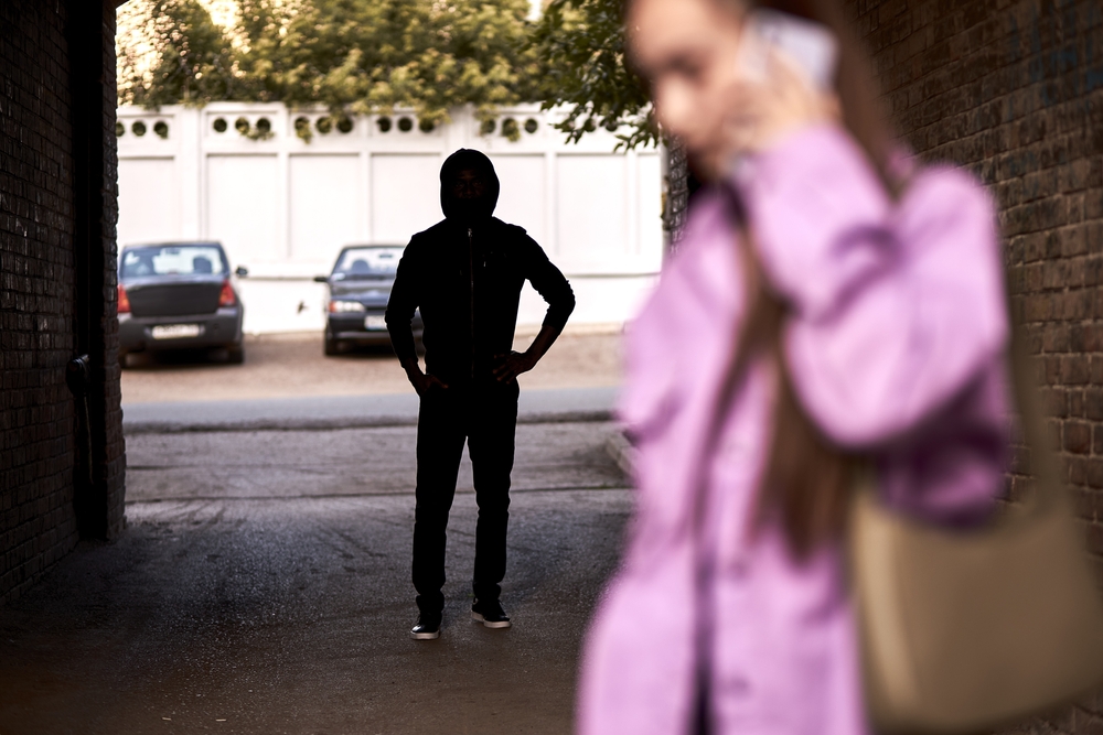 Person in dark, unsecure alley following a woman on phone